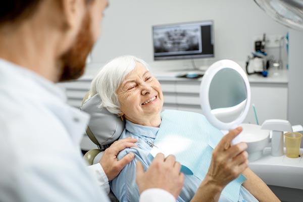 Elderly woman enjoying her new smile with implant supported dentures from Downey Oral and Maxillofacial Surgery in Downey, CA