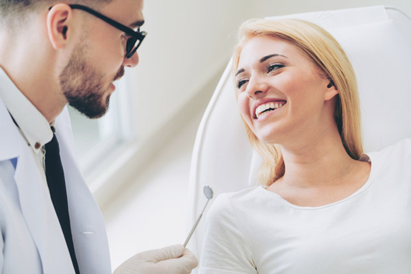 Woman smiling while oral surgeon talks